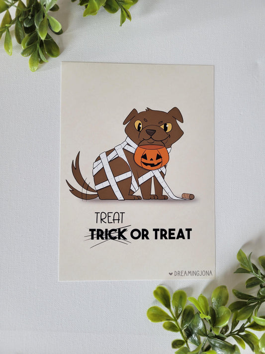 Halloween-themed card with a dog holding a pumpkin and text 'Treat Trick or Treat' on a white background.