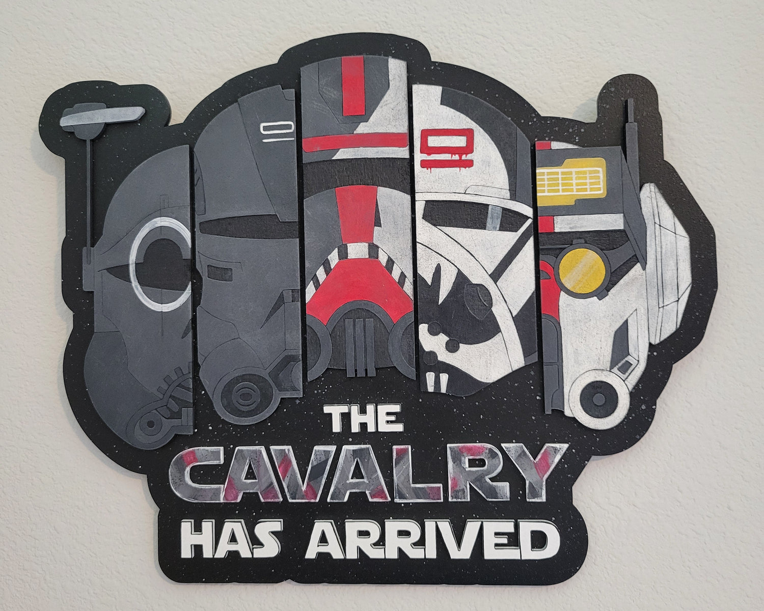 Decorative wall art with Bad Batch clone trooper helmets and 'The Cavalry Has Arrived' text on a plain background