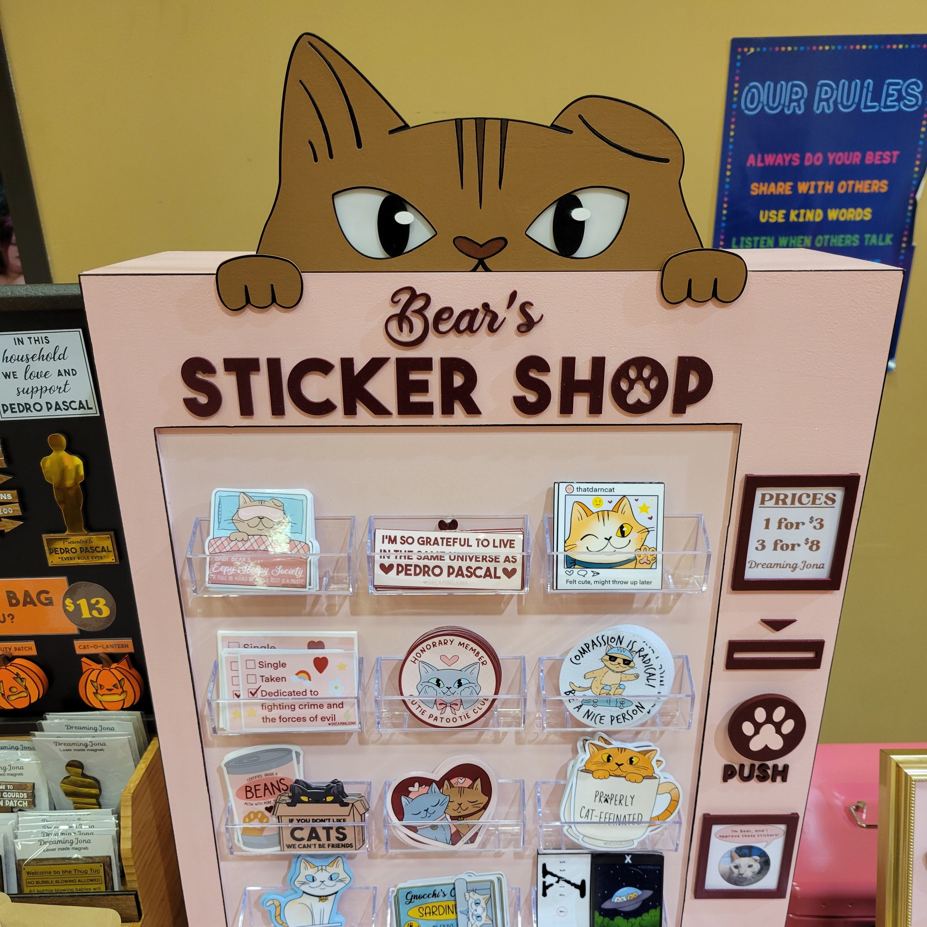 Sticker shop display with various stickers and a cat-shaped sign.