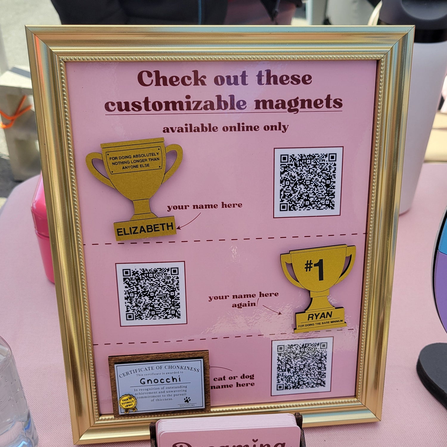Pink frame with customizable magnets and QR codes on a pink surface.