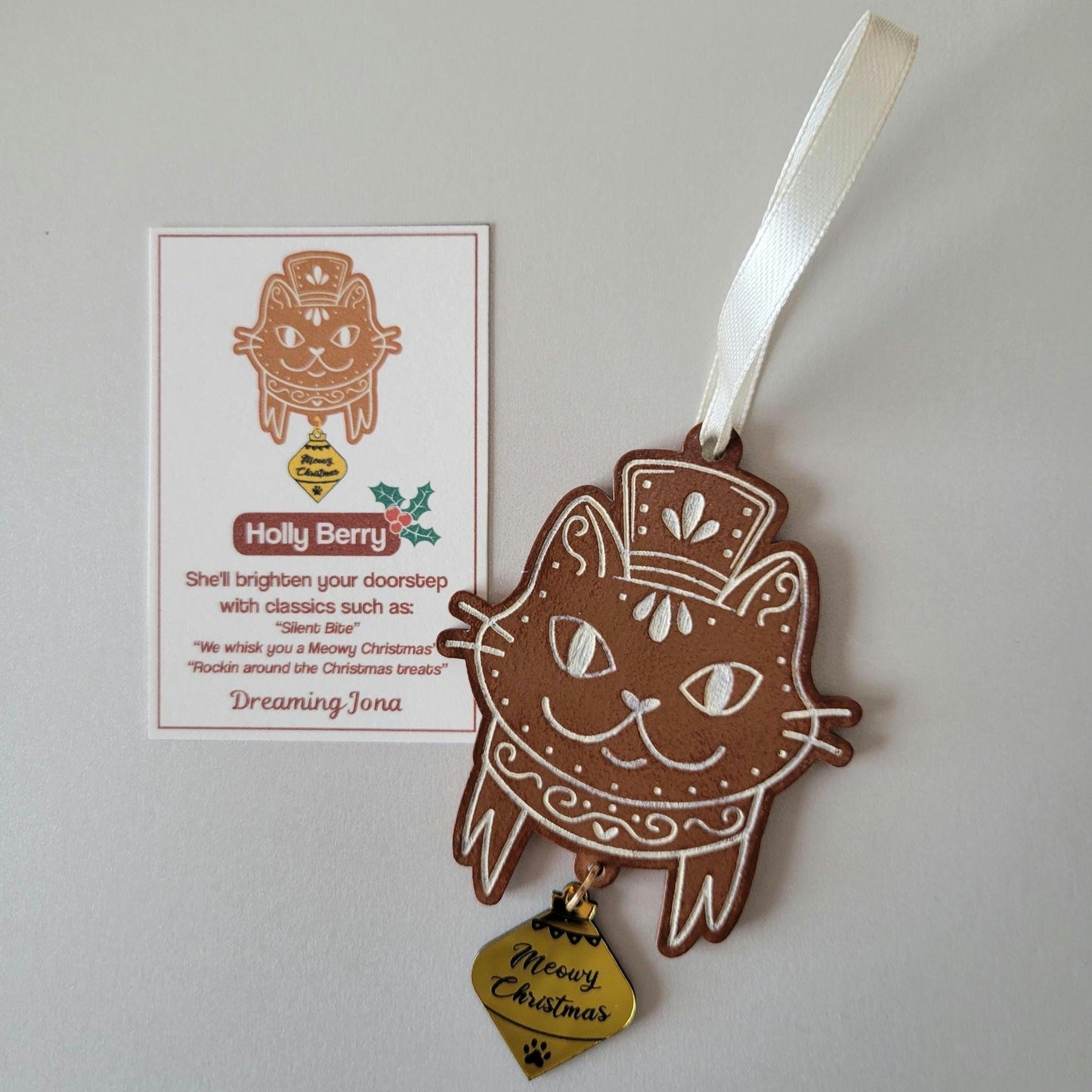 Decorative cat-shaped ornament with a ribbon and a card on a light gray background