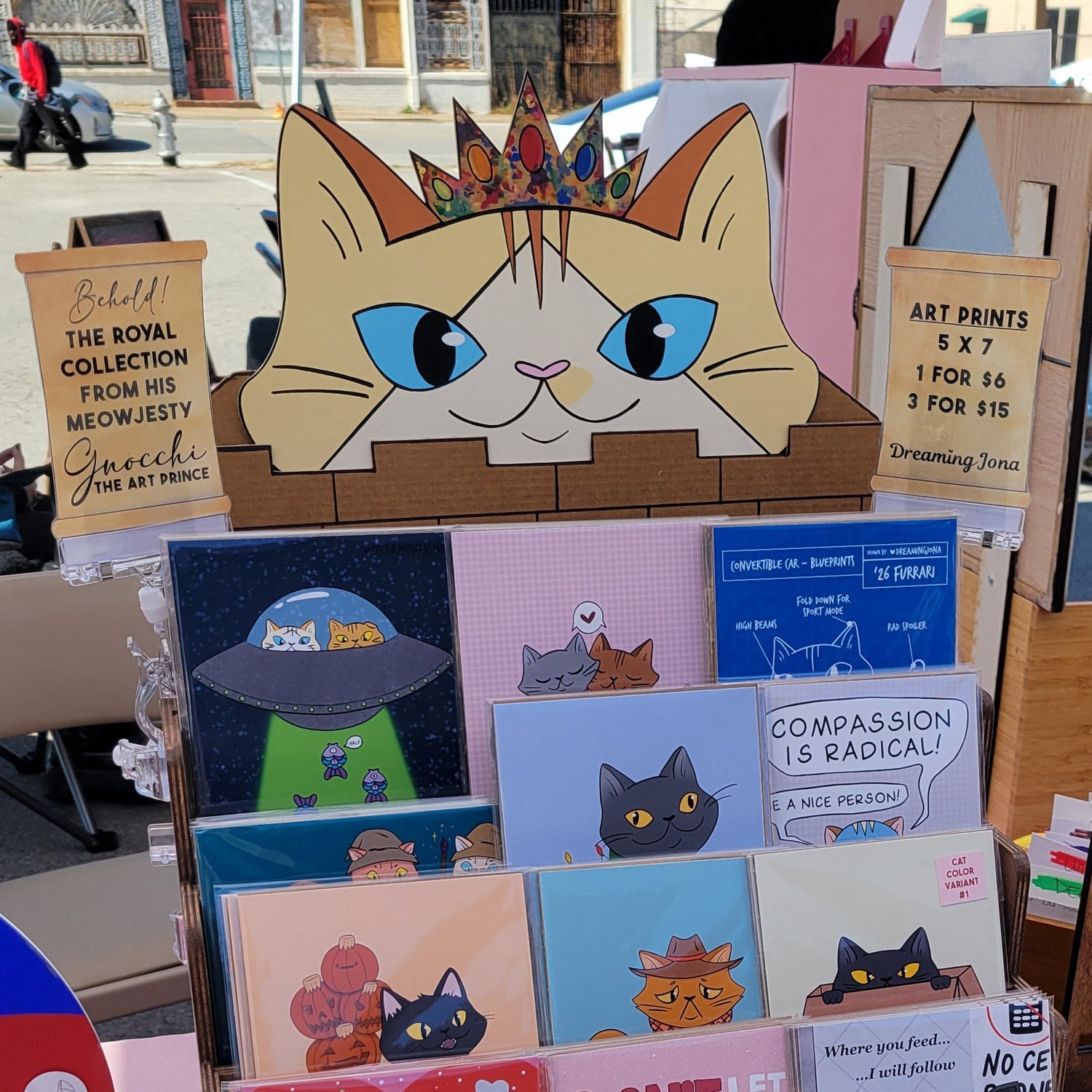 Collection of art prints on a table with a cat shaped sign