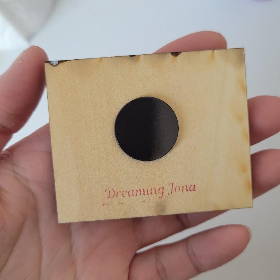 Hand holding a small wooden magnet 