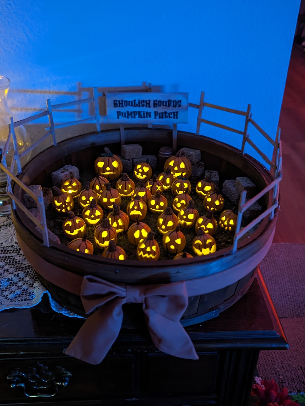 Model of a pumpkin patch with lit jack-o'-lanterns inside a round structure.