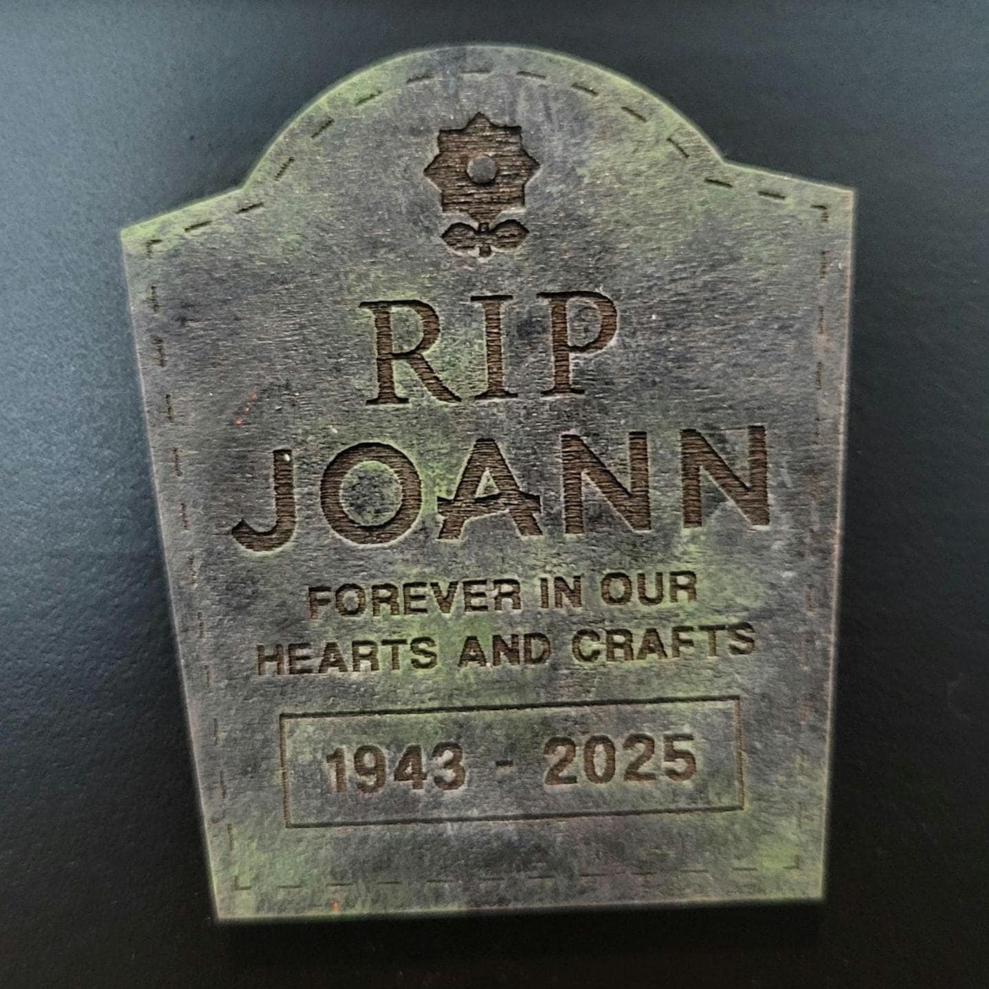 tombstone plaque with 'RIP JOANN' and '1943 - 2025' on a dark background