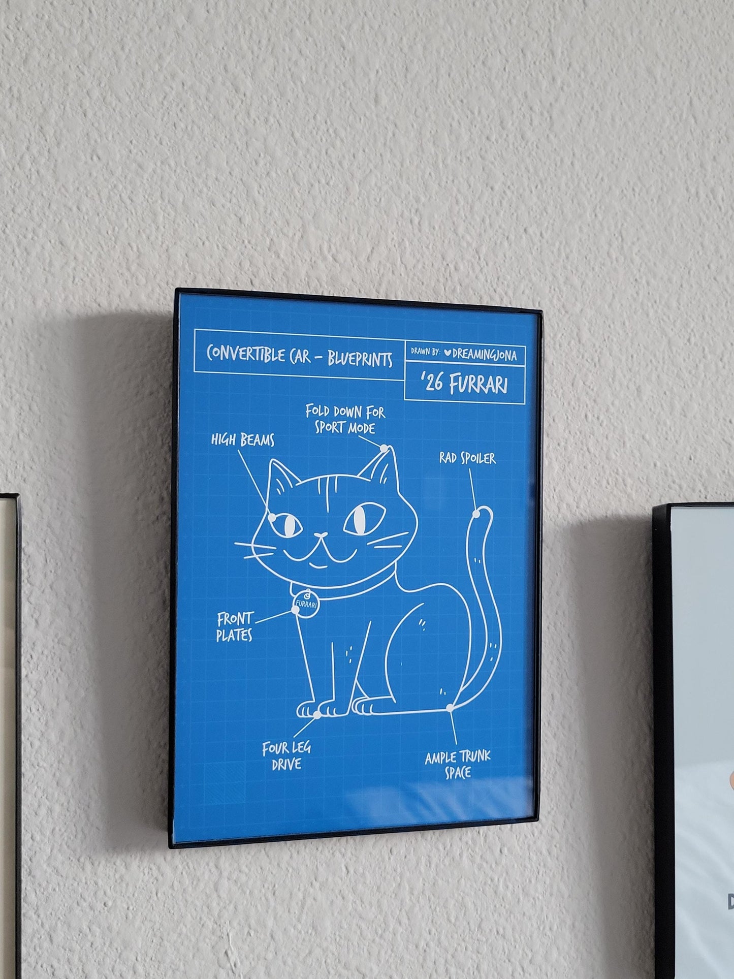 Framed blueprints of a cat design on a wall