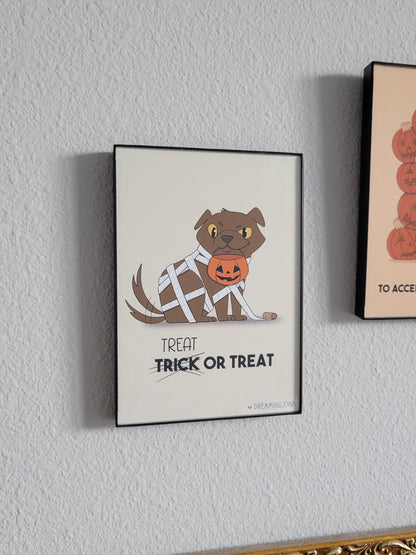 Framed Halloween-themed poster of a dog with a pumpkin on a white wall.