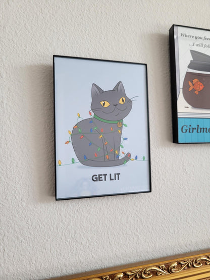 Framed artwork of a cat with colorful lights and 'GET LIT' text on a wall.