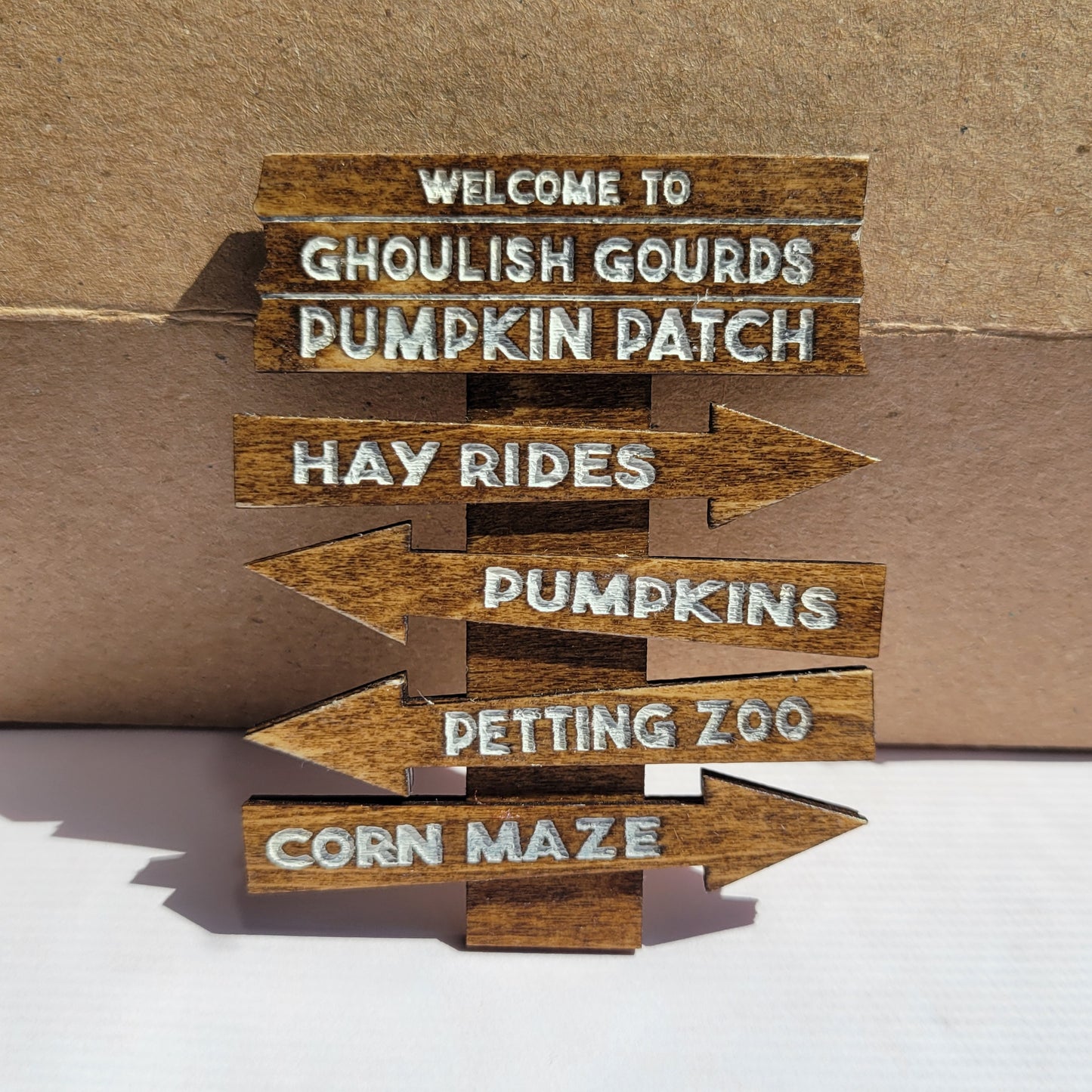 Wooden arrow signs with Halloween-themed text on a cardboard background