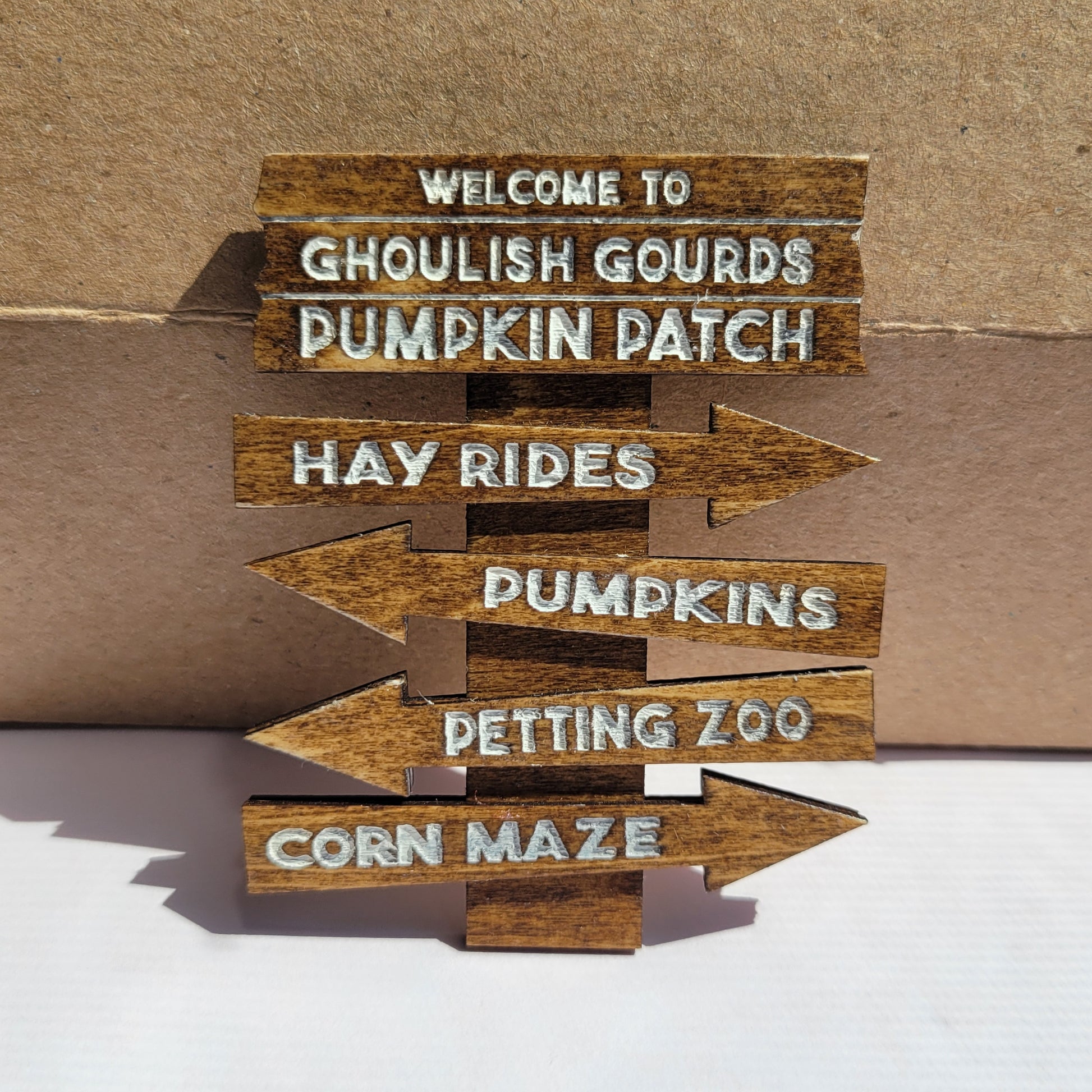 Wooden arrow signs with Halloween-themed text on a cardboard background