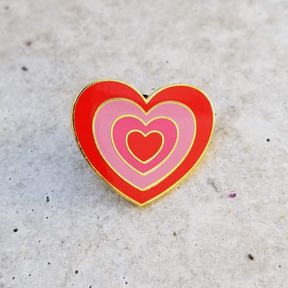 Heart-shaped pin with red and pink hearts on a textured surface