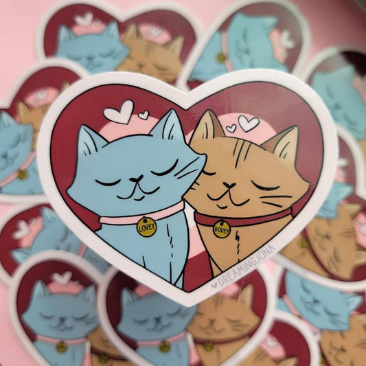 Sticker of two cats in a heart shape with 'LOVE' tags on a pink background