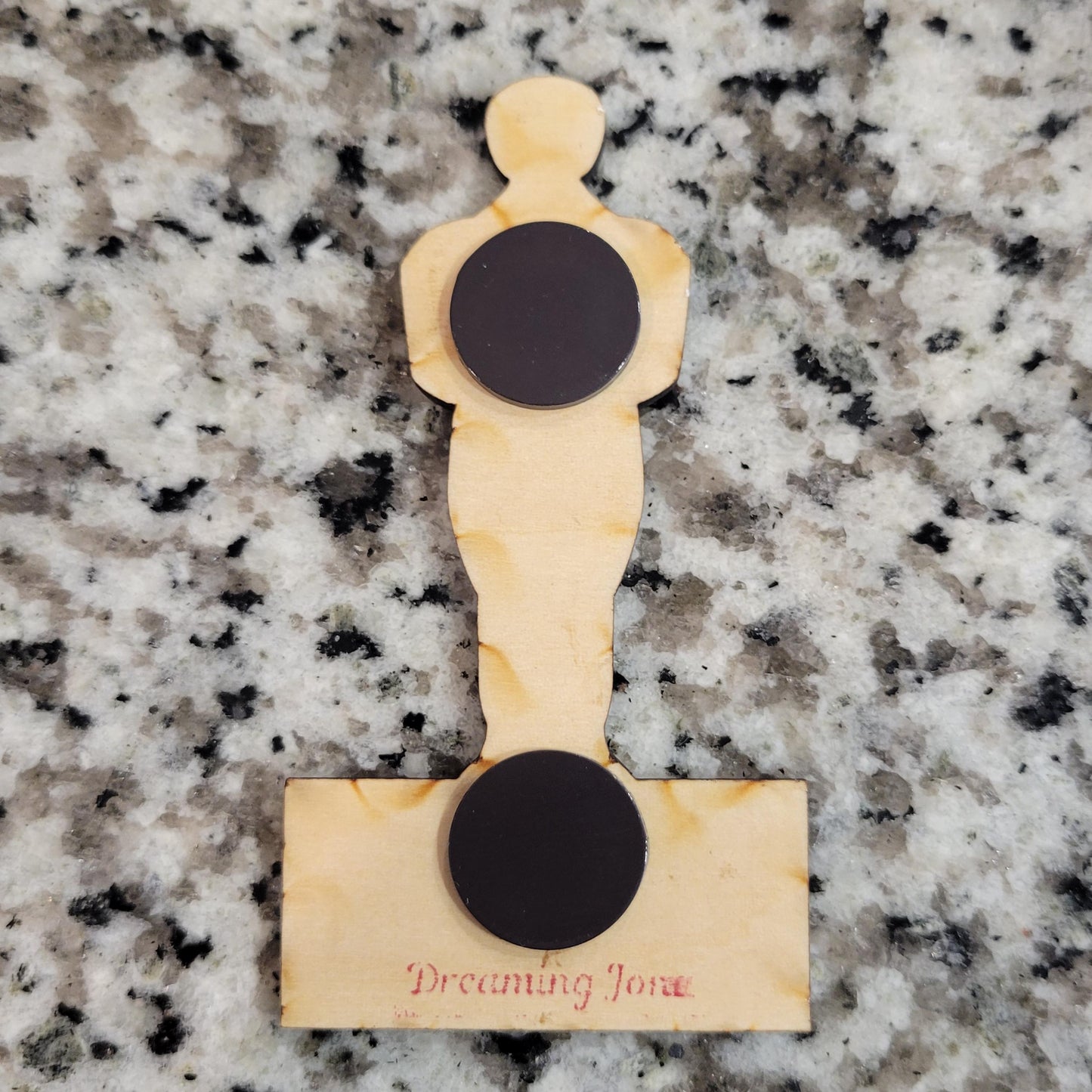 Wooden product with circular black magnets on a granite surface