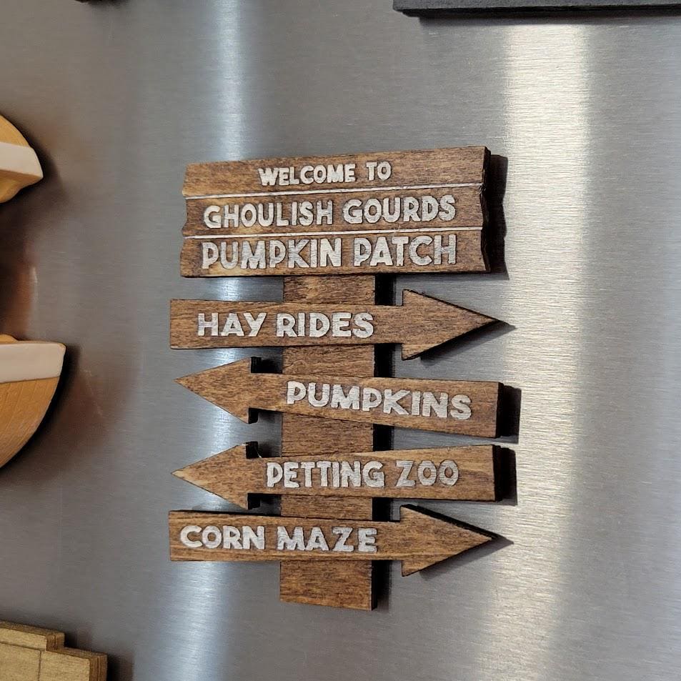 Wooden sign with pumpkin patch directional arrows on a metallic surface