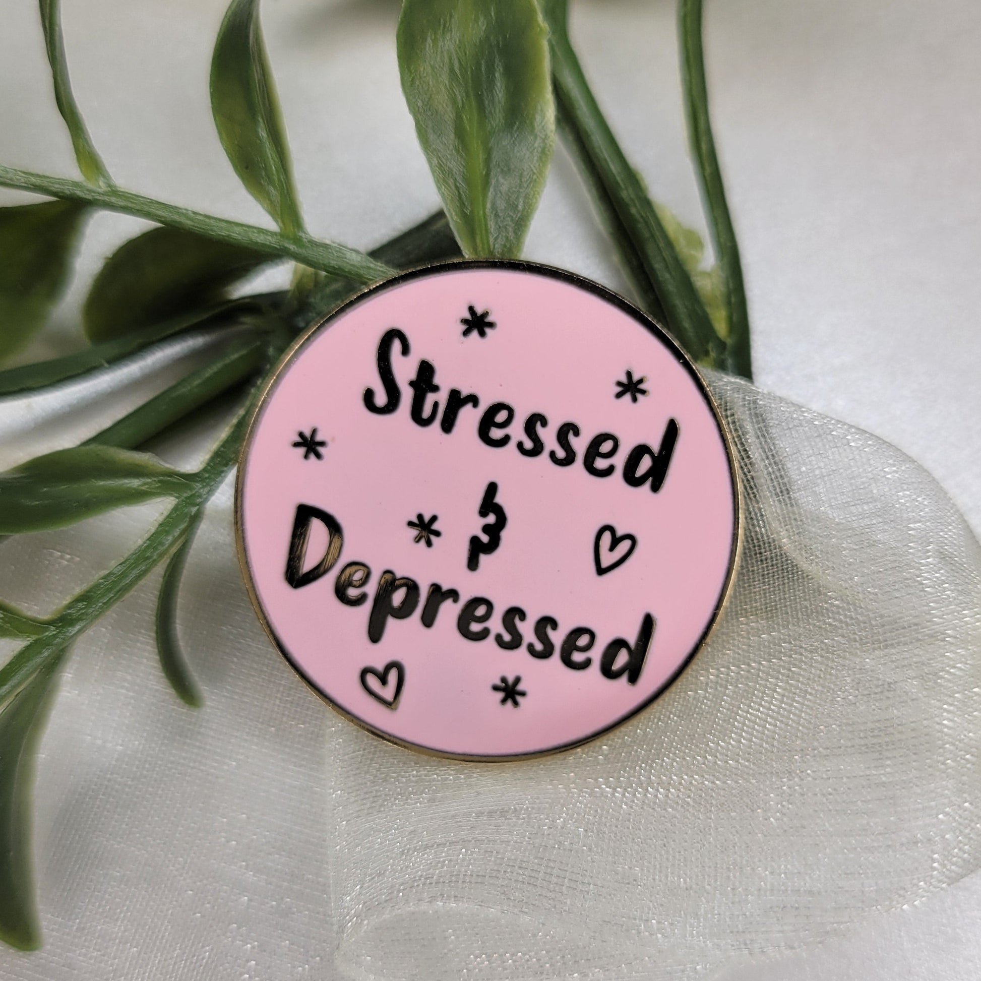 Pink button with text 'Stressed & Depressed' on a white background with green leaves.
