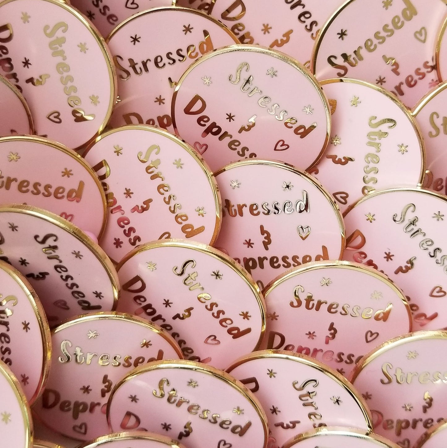 Pink and gold pin buttons with 'Stressed' and 'Depressed' text on a pink background