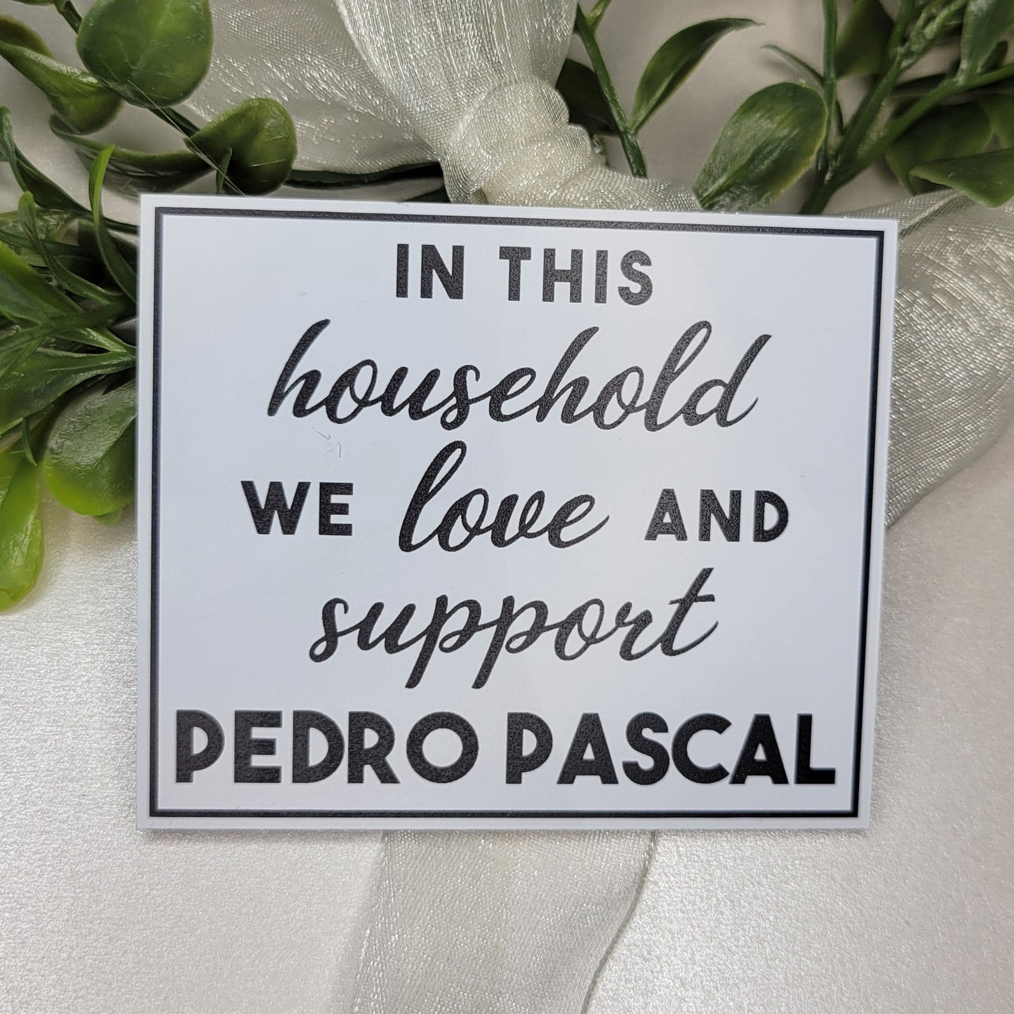 Decorative sign with black text and greenery on a white background